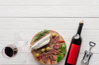 şişe ve bardak kırmızı şarap ile çeşitli et meze Beyaz ahşap yüzeyde üstten görünüm
