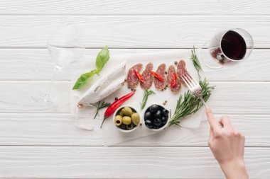 kadın, kırmızı şarap ve et aperatifler Beyaz ahşap yüzey üzerinde cam kadeh kırpılmış