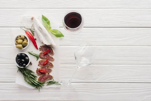 赤ワインと各種肉スナック白い木製のテーブルの上のグラスと食品成分 — ストック写真