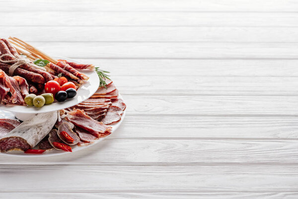 close up view of delicious meat appetizers with olives on white wooden tabletop
