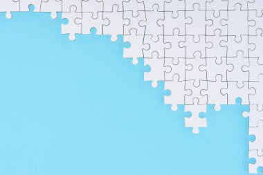 düz lay mavi zemin üzerine beyaz puzzle parçaları ile