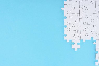düz lay mavi zemin üzerine beyaz puzzle parçaları ile