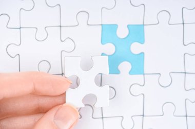 cropped shot of woman with white puzzles pieces on blue background clipart