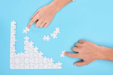 Erkek ve kadın mavi zemin, işbirliği kavramı üzerinde beyaz puzzle parçaları ile atış kırpılmış