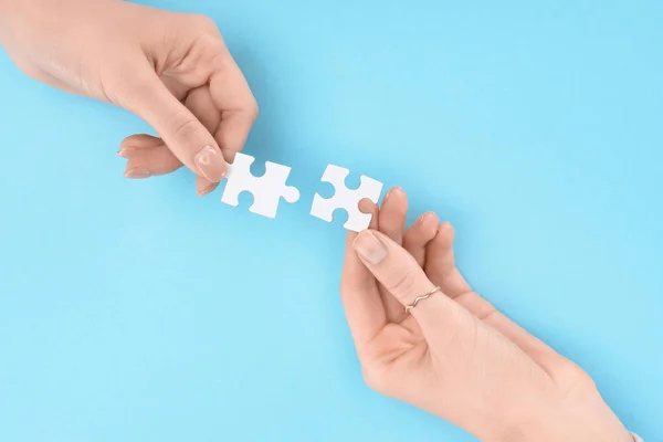 青い背景 業務協力とチームワークの概念に手で白のパズルを保持する女性のクロップ撮影 — ストック写真