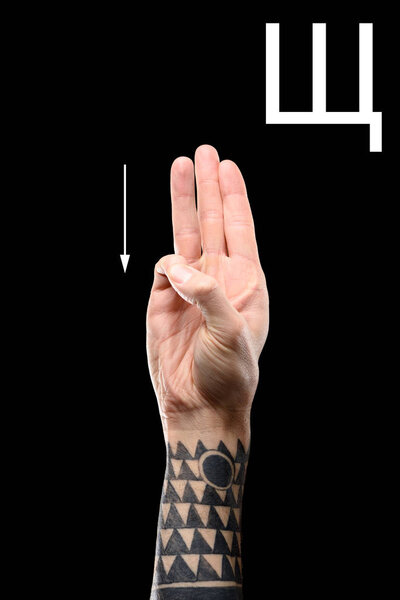 partial view of male tattooed hand showing cyrillic letter, deaf and dumb language, isolated on black