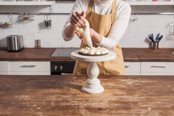 グルメな自家製ケーキとクリームを飾るエプロン女性の部分的なビュー — ストック写真