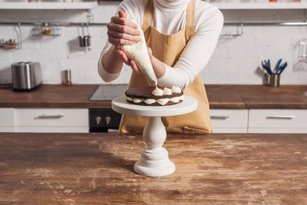 グルメ甘いケーキとクリームを飾るエプロンの女性の中央部 — ストック写真
