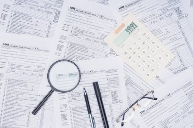 arka plan üzerinde hesap makinesi, büyüteç ve ileti örneği ile vergi formlarını üstten görünüm