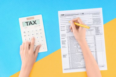 cropped view of woman using calculator with word 'tax' and filling tax form on blue and yellow background clipart
