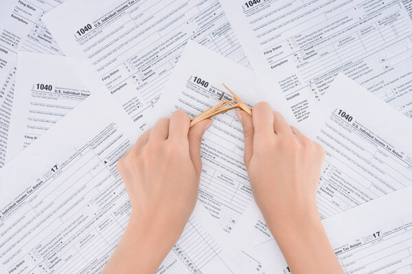 cropped view of stressed woman breaking pencil with tax forms on background 