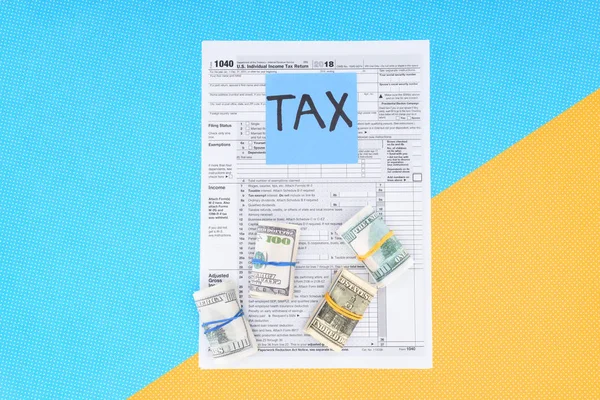 税務フォーム お金ロール 青と黄色の背景に 単語カードのトップ ビュー  — 無料ストックフォト