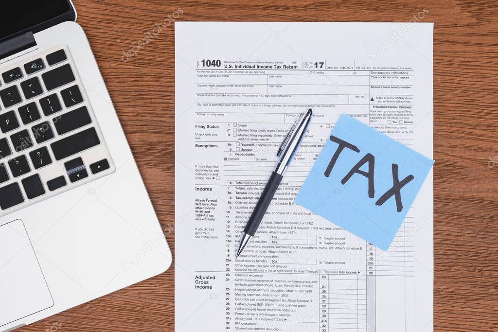 top view of tax form, laptop and blue card with 'tax' word on desk