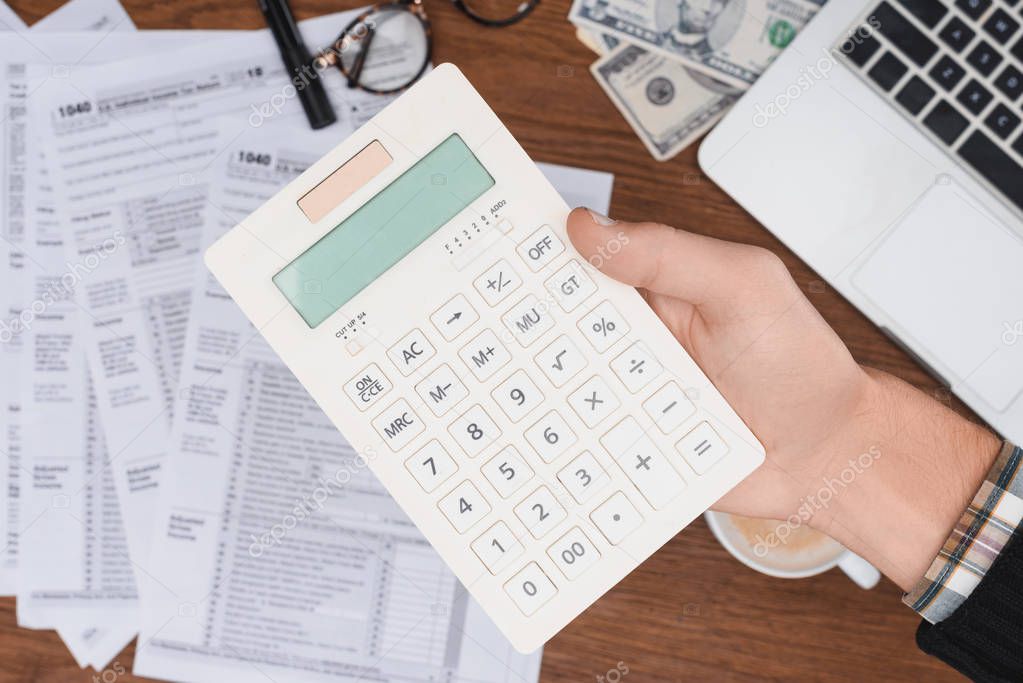 selective focus of man using calculator with tax forms on background