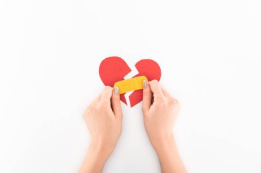 partial view of woman holding broken red heart with medical patch symbol isolated on white, st valentine day concept clipart