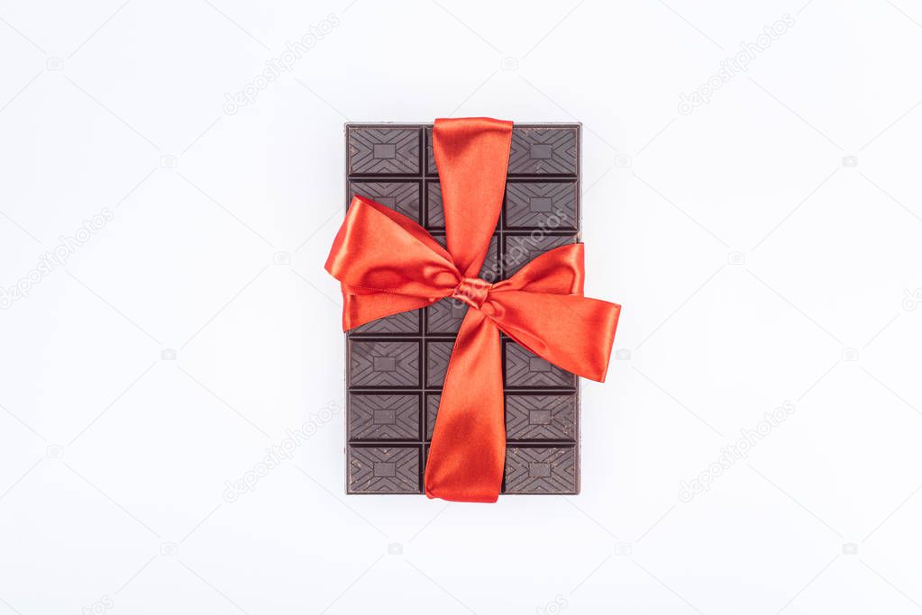 top view of delicious chocolate wrapped by festive ribbon isolated on white, st valentine day concept