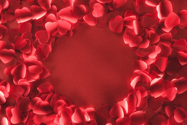 вид сверху на красивый круглый кадр из декоративных лепестков в форме сердца на красном фоне
 