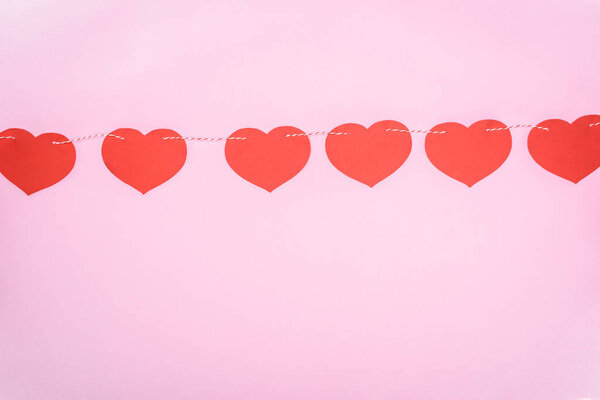 beautiful decorative red hearts hanging on rope on pink background, valentines day concept