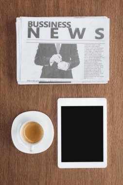 top view of cup of coffee, tablet with blank screen and business newspaper on wooden tabletop clipart