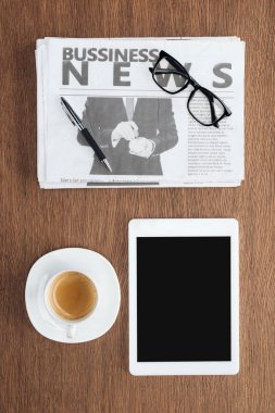 kahve, tablet boş ekran ve ahşap masa üzerinde iş gazete ile yükseltilmiş görünümünü