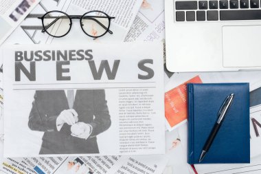Gözlük, kalem ve defter ve laptop yükseltilmiş görünümünü üzerinde Gazeteler