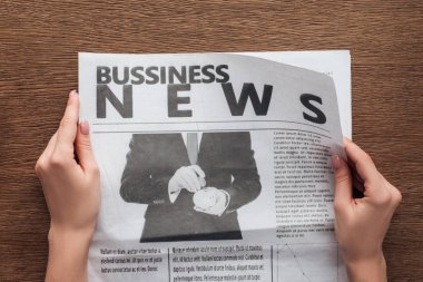 cropped image of journalist reading business newspaper at wooden table clipart