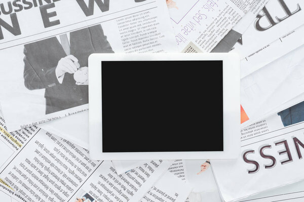 top view of tablet with blank screen on business newspapers