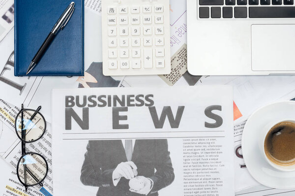 повышенный вид очков, ручки, калькулятора и ноутбука и ноутбука на газетах
