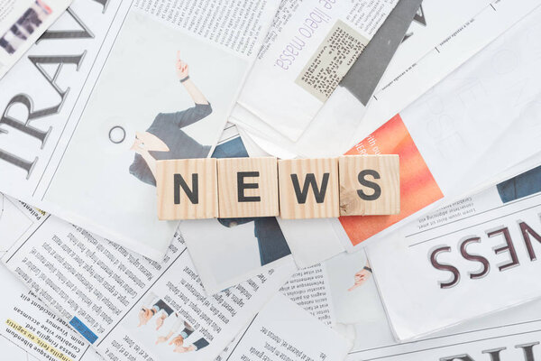 top view of wooden cubes with word news on newspapers