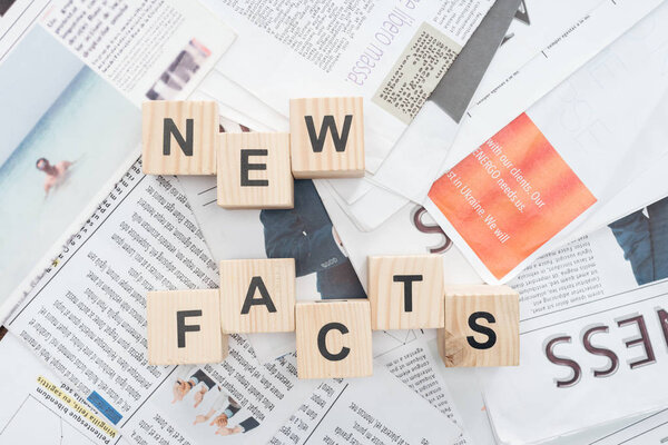 top view of wooden cubes with words news facts on newspapers