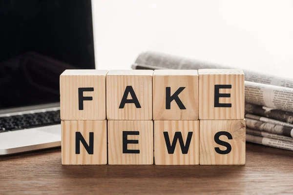 Holzwürfel Mit Wörtern Fake News Laptop Und Zeitungen Auf Holztischplatte — Stockfoto