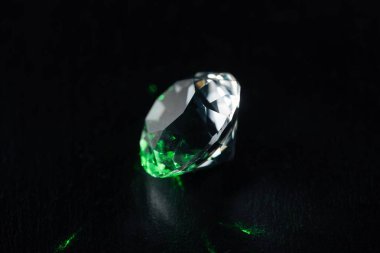 illuminated diamond with green light on black background clipart