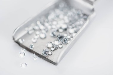 selective focus of small diamonds on spatula isolated on grey clipart
