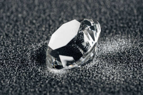 крупный план чистого алмаза на сером текстурированном фоне
 