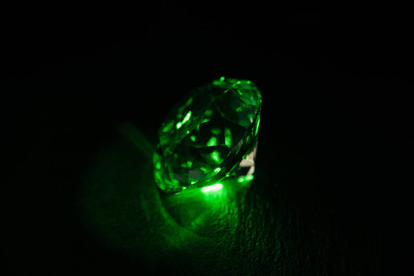 illuminated diamond with bright green neon light on dark background