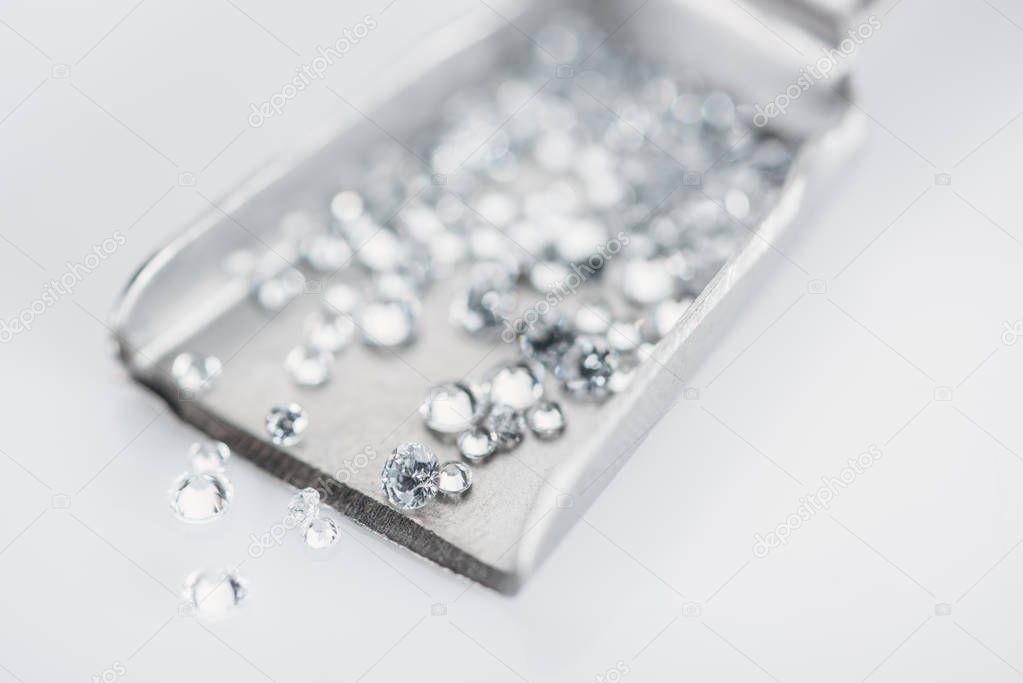 selective focus of small diamonds on spatula isolated on grey