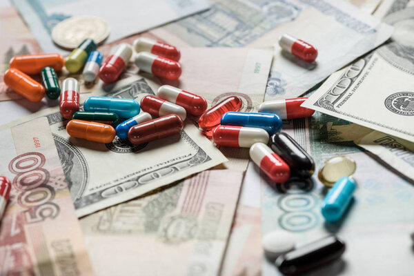close up of colorful pills on cash background