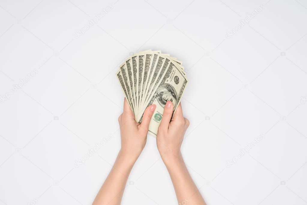 partial view of woman holding dollars in hands isolated on grey