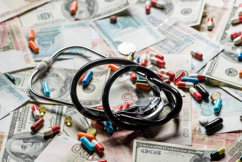 Close up of colorful pills and stethoscope on cash background