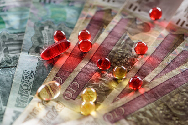close up of bright oval and round pills on cash background