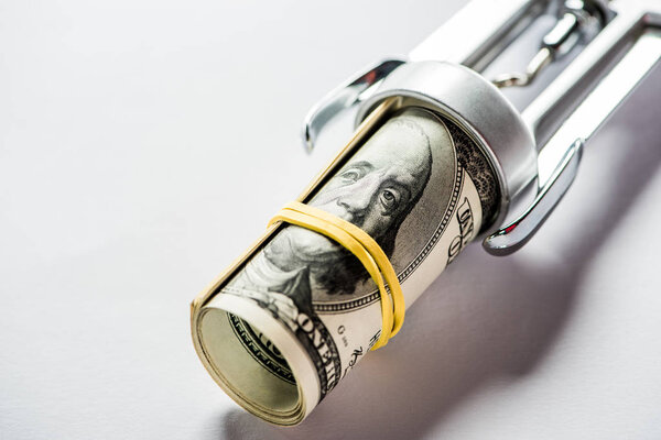 close up of rolled dollar banknotes in corkscrew on grey background