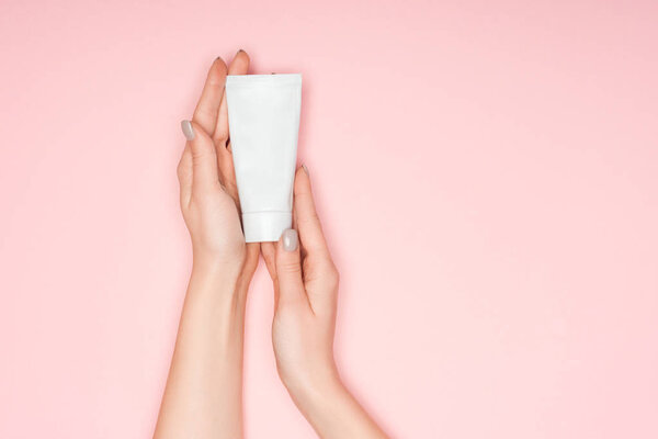 top view of female hands with hand cream isolated on pink