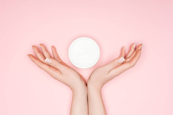 cropped view of female hands with body cream isolated on pink