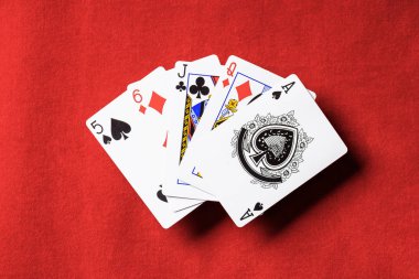 Kırmızı poker masası ve gelişeceğini iskambil farklı takım elbise ile üstten görünüm