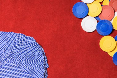 top view of red poker table with multicolored chips and unfolded cards 