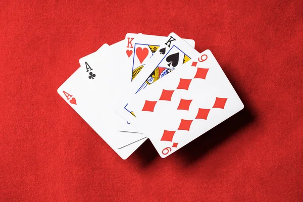 Kırmızı poker masası ve gelişeceğini iskambil farklı takım elbise ile üstten görünüm