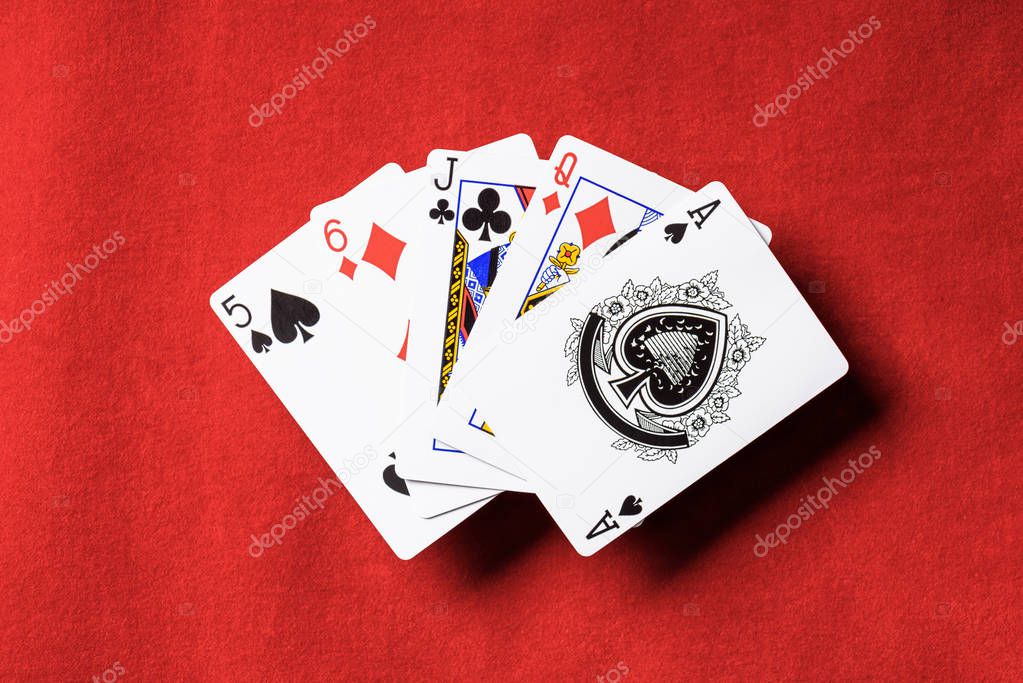 top view of red poker table and unfolded playing cards with different suits