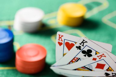 selective focus of playing cards with chips and green poker table on background clipart