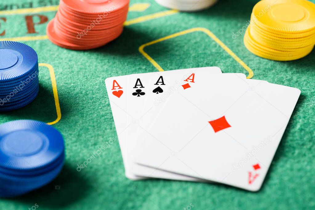 selective focus of green poker table with four aces playing cards and chips 