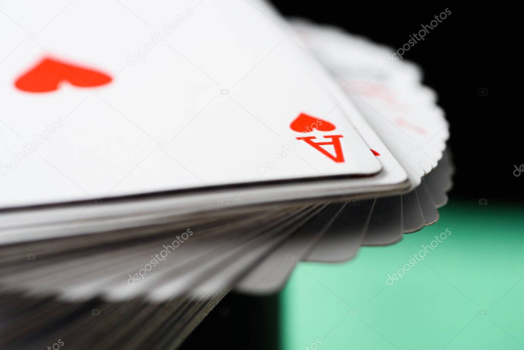 selective focus of ace playing card with hearts suit in deck on green background